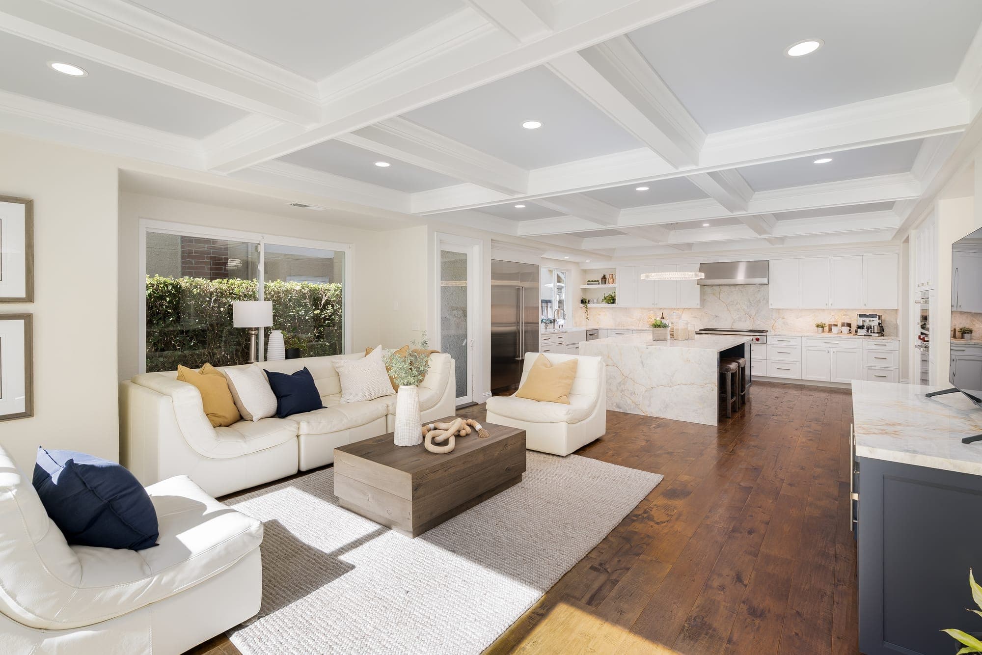 The family room opening to the kitchen beneath a continuous coffered ceiling.