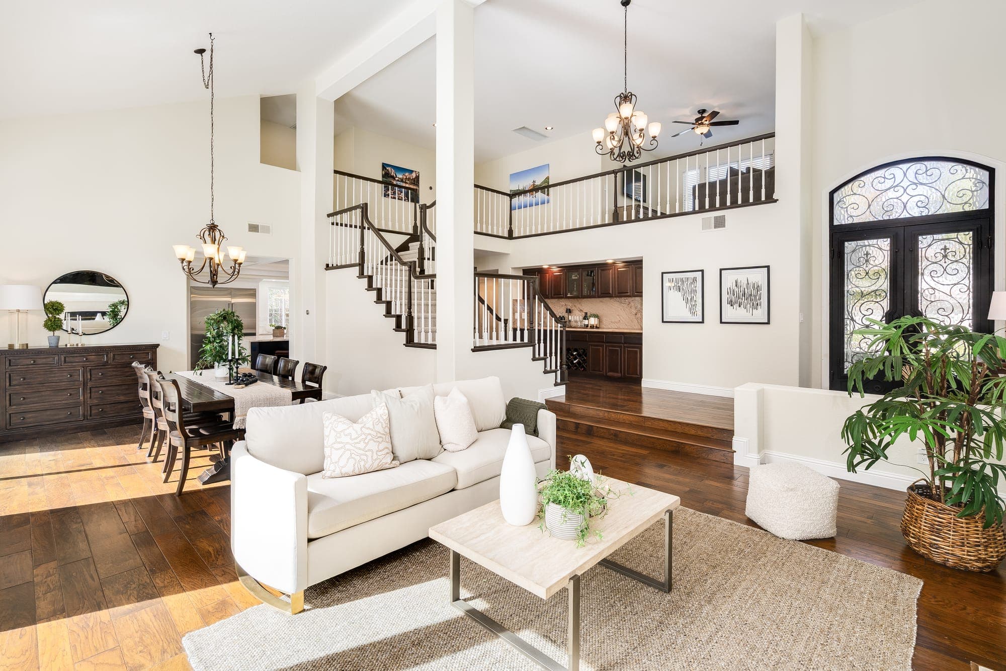 The living room under a two-story ceiling, with the curved staircase and front doors beyond.