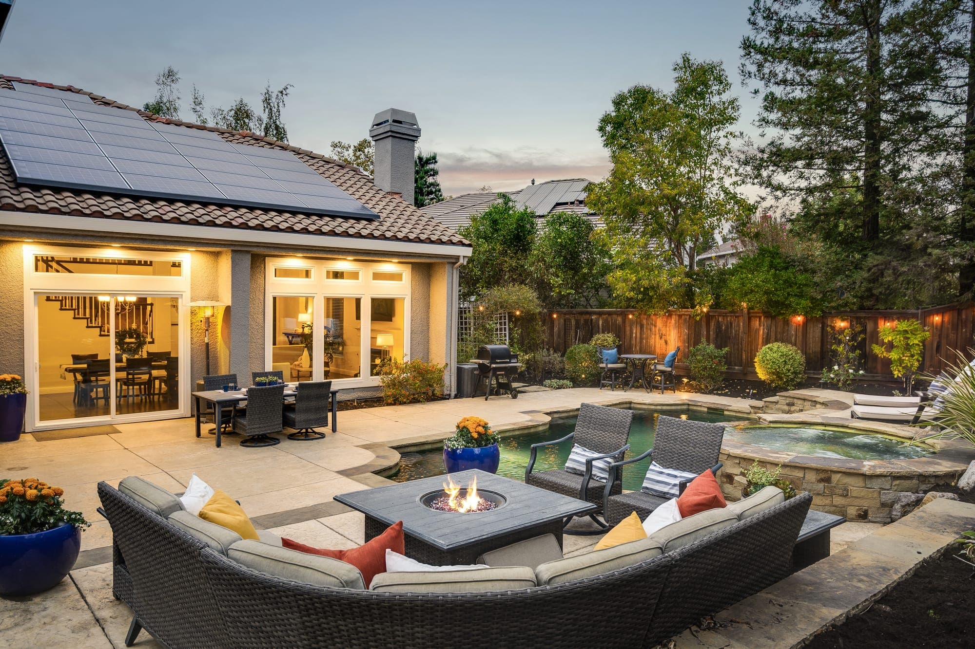The backyard lounge at dusk, with the lit family room and kitchen behind.