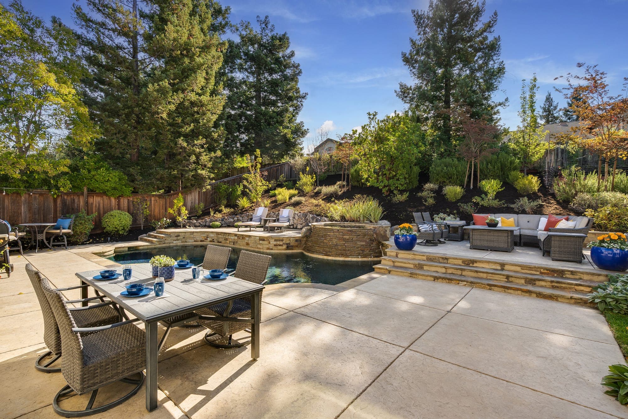 An outdoor dining table on the patio beside the pool and raised lounge.