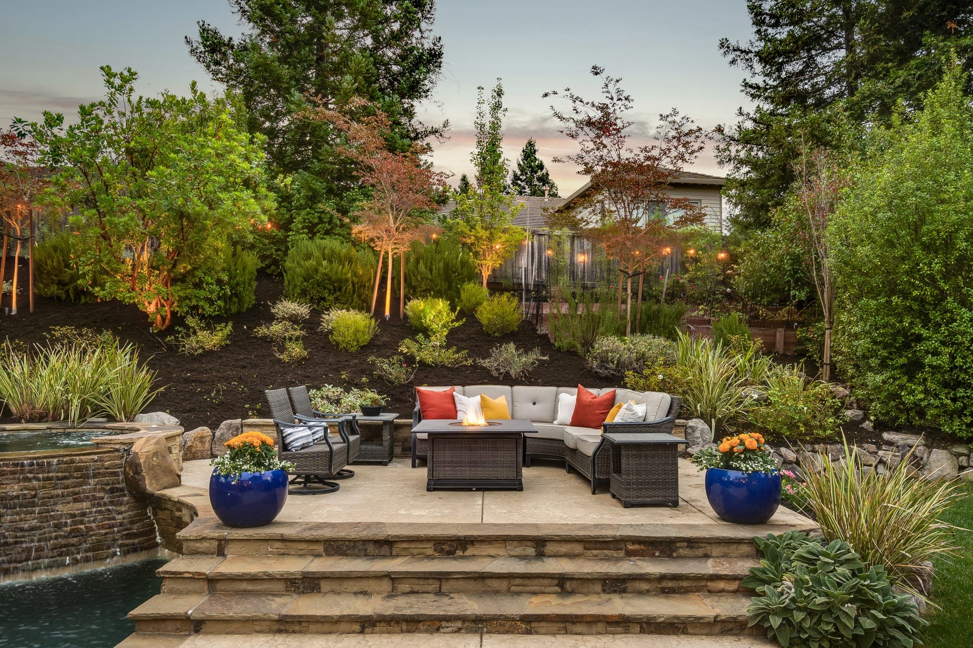 The raised lounge at dusk, with landscape lighting in the planting behind.