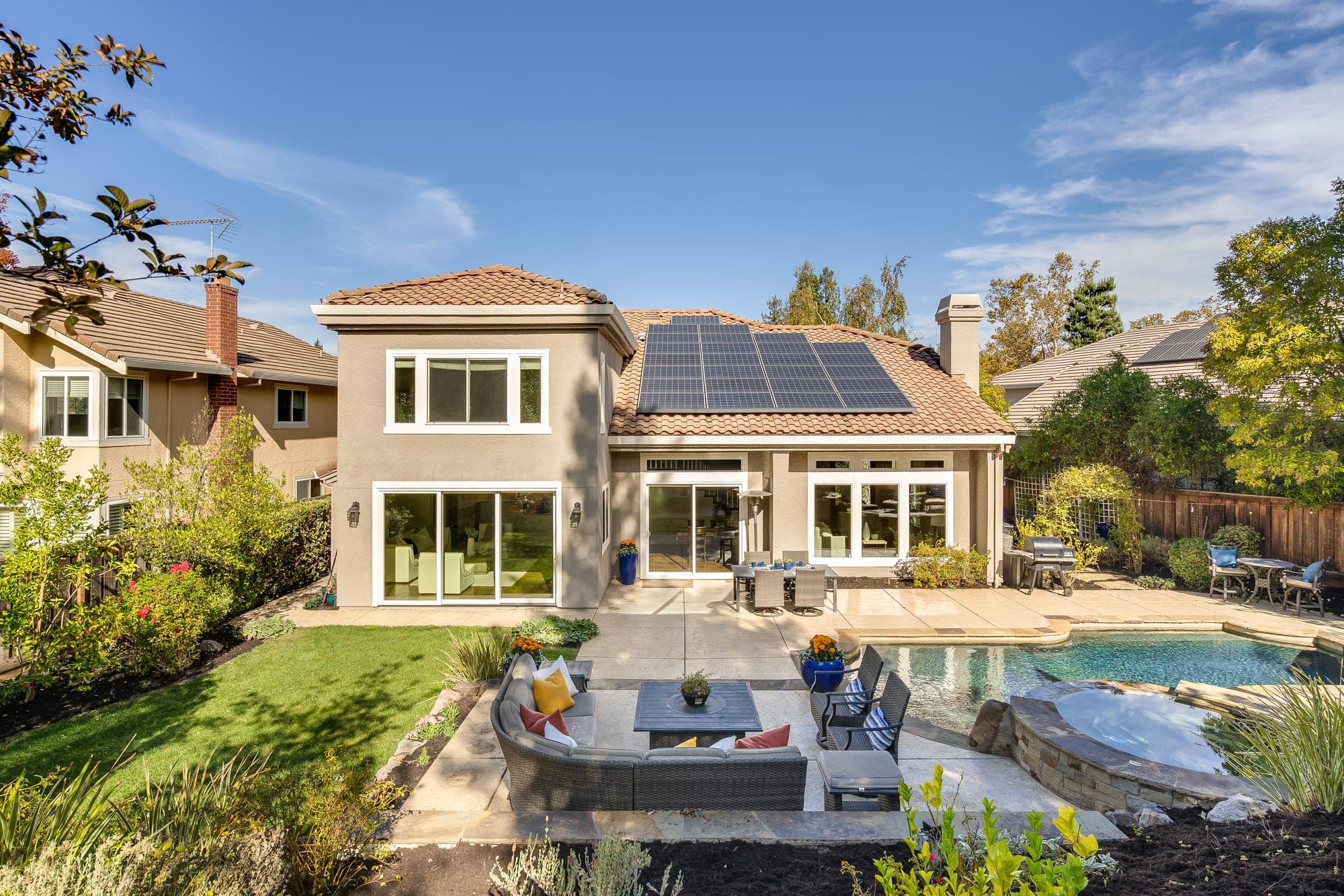 The back of the home seen across the lounge, pool, and patios.