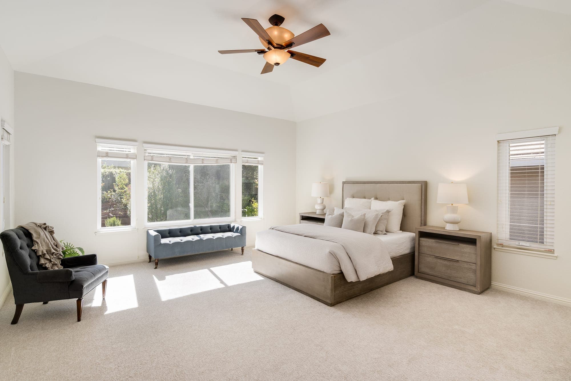 The primary bedroom with a sitting area and windows to the trees.