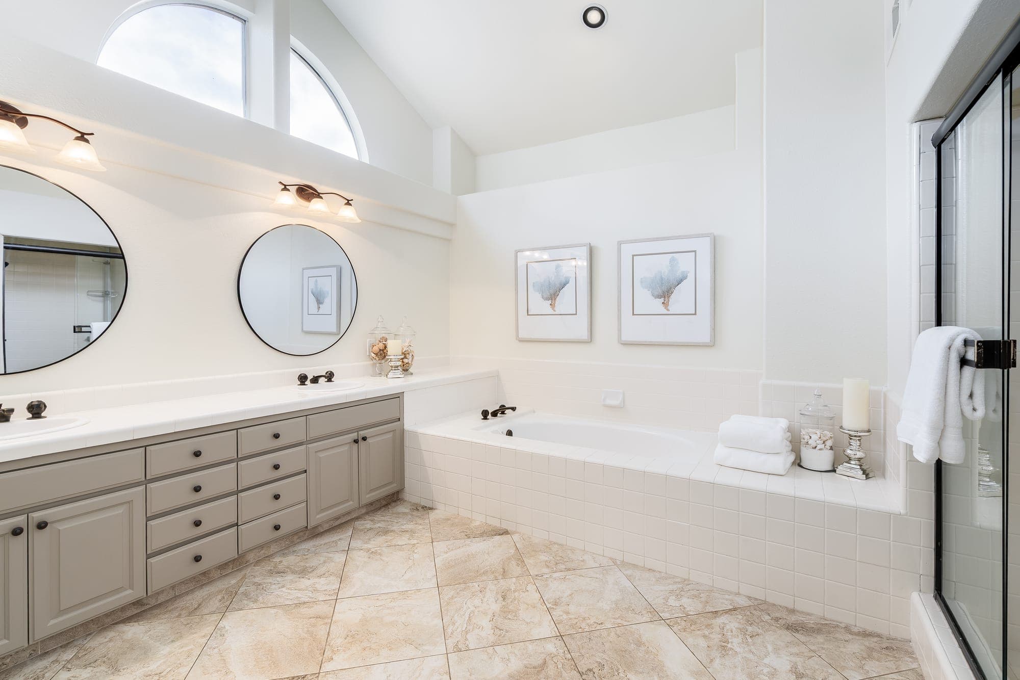 The primary bath with dual vanities, a soaking tub, and arched clerestory windows.