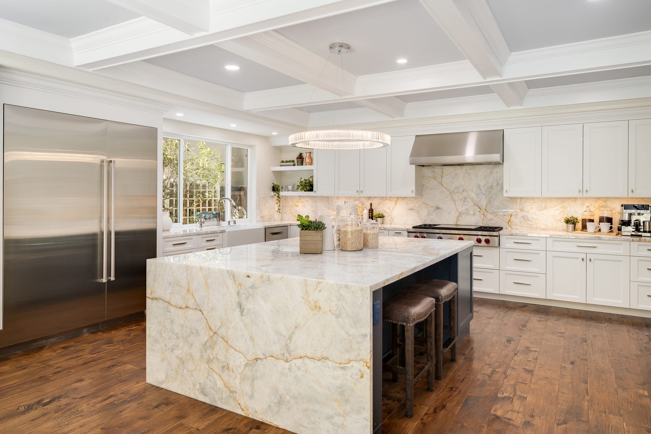 The kitchen's quartzite waterfall island under a coffered ceiling.